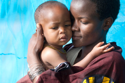 Mother holding child in front of RBM blue mosquito net